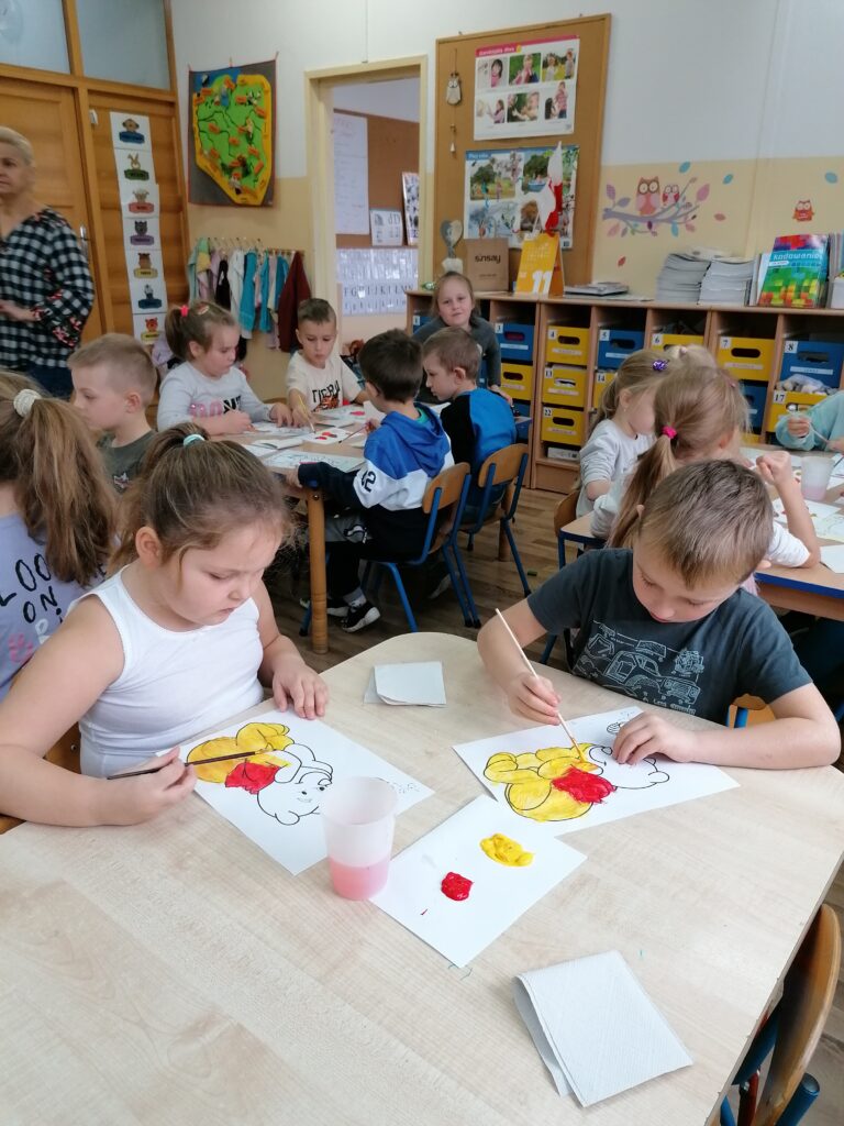 Malowanie obrazka Kubusia Puchatka farbami przez chłopca i dziewczynkę