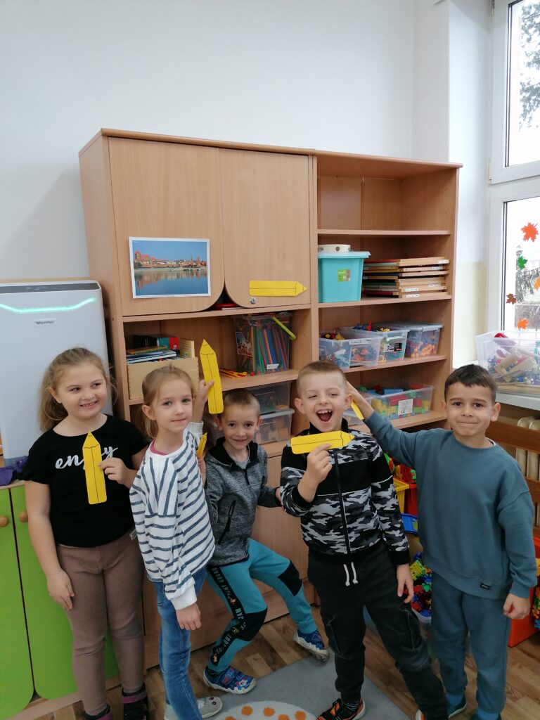 Dwie dziewczynki i troje chłopców tworzyło żółty zbiór kredek. 